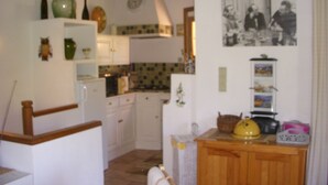 Una cocina con armarios blancos, una encimera de madera y diversos utensilios.