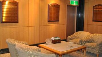 Un vestíbulo con sillones estampados, un mostrador de recepción de madera y un ascensor.