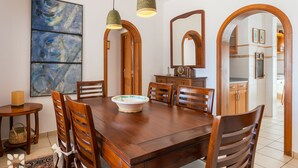 A dining area with a wooden table, chairs, a bowl, and a painting on the wall. - Villa SANDRO by Abahana Villas (Benissa)