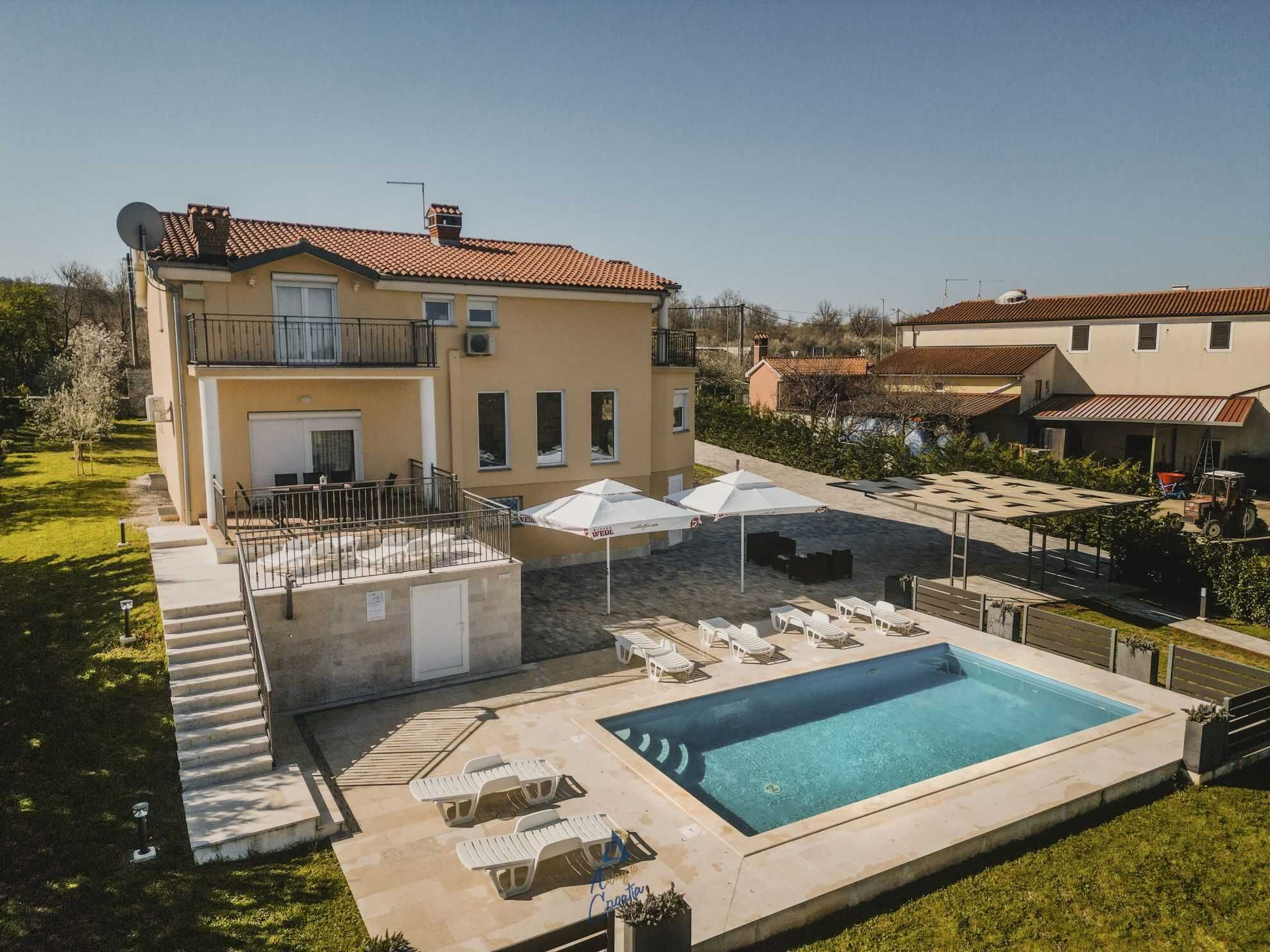 Un edificio a due piani con piscina, area salotto esterna e patio coperto.