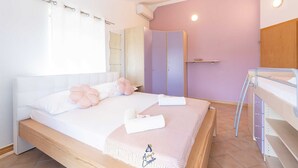Une chambre à coucher comprenant un lit, une table de chevet, une armoire et un lit superposé.