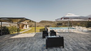 Une terrasse sur le toit avec une piscine, des espaces de détente en plein air et une vue sur le paysage environnant.