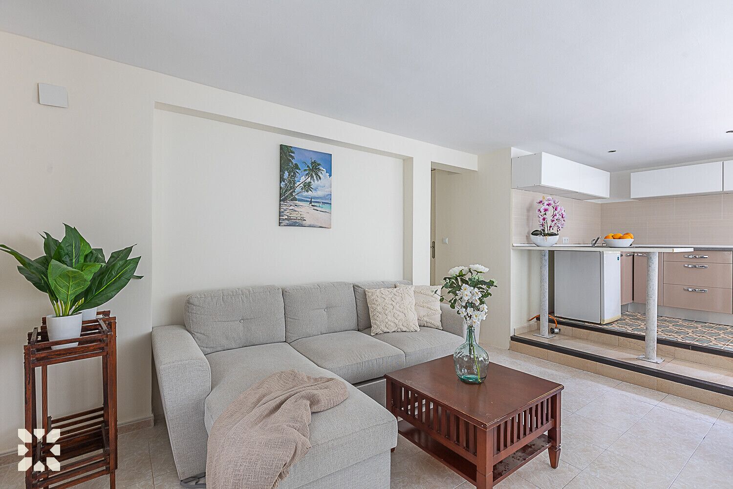 A modern living room with a sofa, a coffee table, and a painting of a beach scene.