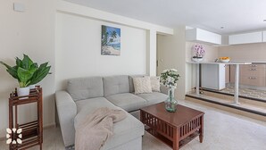 A modern living room with a sofa, a coffee table, and a painting of a beach scene. - Villa RICA by Abahana Villas (Calpe)