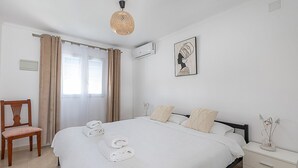 A bedroom with a bed, a chair, a bedside table, and a wall-mounted air conditioner. - Villa RICA by Abahana Villas (Calpe)