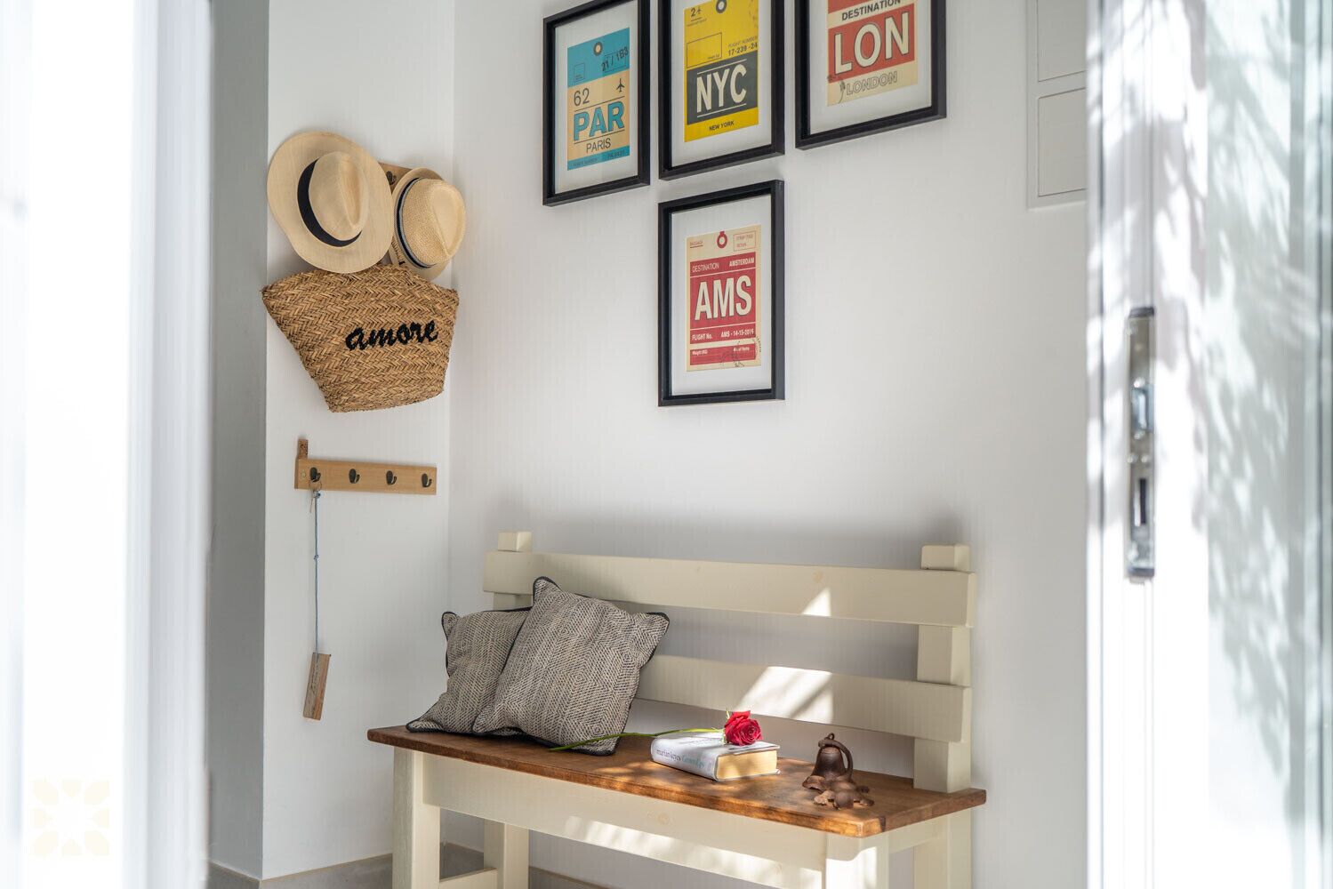 A cozy room with a wooden bench, a basket labeled "amore", and framed travel destination signs.