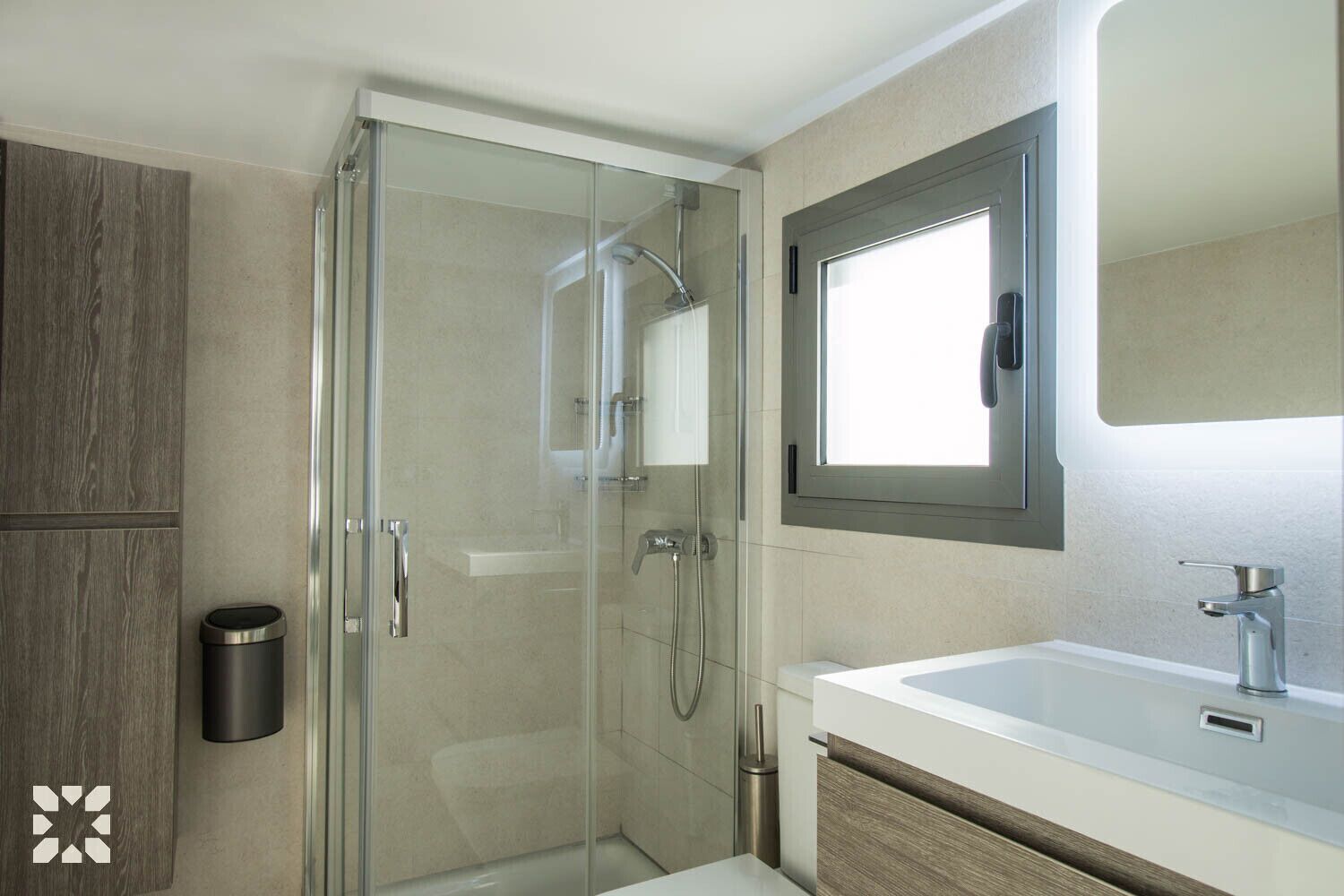 Un bagno moderno con doccia vetrata, lavandino bianco e specchio sopra.