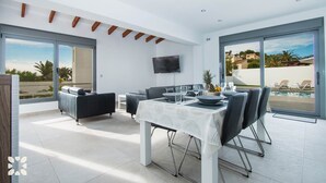 A modern dining area with a table set for four, a sofa, and a TV mounted on the wall.