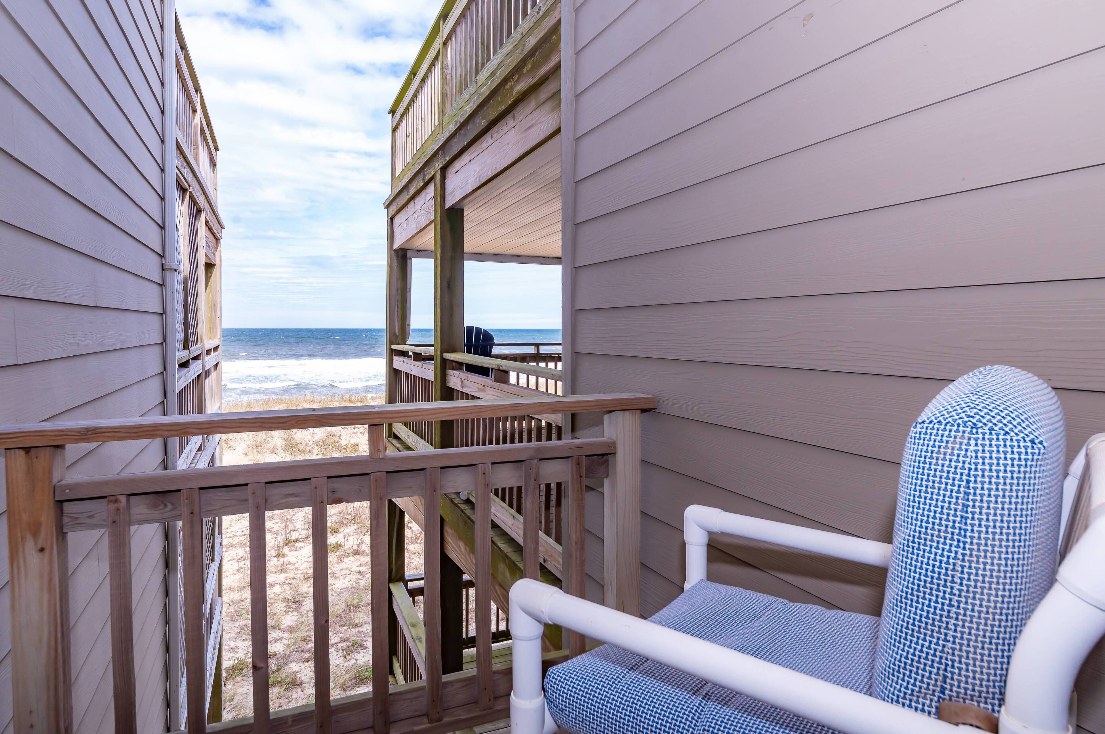 Une vue sur la plage depuis une terrasse en bois avec une chaise.
