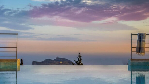 An infinity pool with a view of a distant island and a sunset sky. - Villa PUNTA VISTA by Abahana Villas (Benitachell)