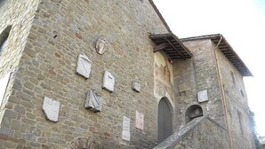 Un edificio de piedra con una escalera que lleva a la entrada, varias ventanas y un pequeño balcón.