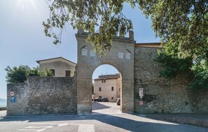 A stone archway leading to a building with a flat roof, a parking sign, and a no parking sign. - Ville Fontanelle | Villa Anna in Bettona, Perugia, with a Pool and Tennis Court (Bettona)