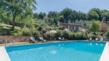 Relax by the serene pool surrounded by lush greenery and comfortable lounge chairs.