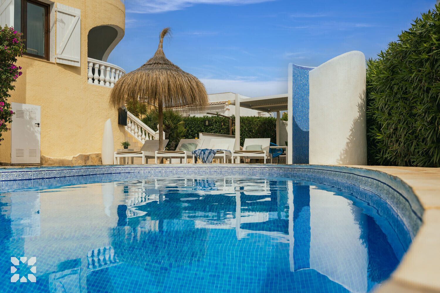 A swimming pool with lounge chairs and a thatched umbrella.
