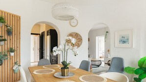 Uma área de jantar moderna com mesa de madeira, cadeiras brancas e um lustre.