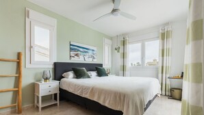 Quarto com cama, mesa de cabeceira, abajur e vista para o exterior.