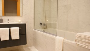 Een bad/douchecombinatie, een haardroger, badjassen, een bidet