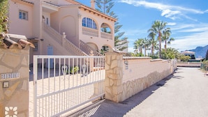 A Mediterranean-style building with a gated entrance, stone walls, and a clear sky. - Villa LUNA FELIZ by Abahana Villas (Calpe)