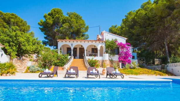 A villa with a swimming pool, outdoor seating, and a staircase leading to the entrance.