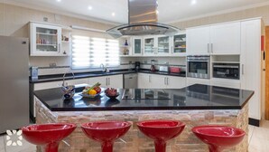 Een moderne keuken met een groot eiland, witte kasten en een betegelde achterwand.