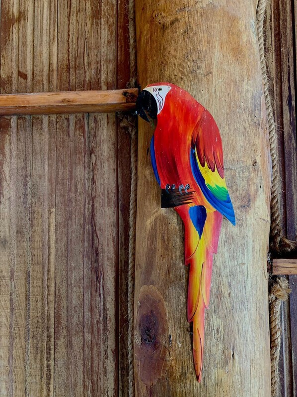 Una escultura de pájaro de madera, colorida, adosada a una estructura de madera.