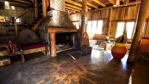 A rustic interior with a stone fireplace, wooden beams, and a star-shaped floor design. - Pousada Chapada dos Veadeiros (Alto Paraíso de Goiás)
