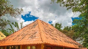 A rustic wooden building with a tiled roof, a stone-paved courtyard, and a mural on the side. - Pousada Chapada dos Veadeiros (Alto Paraíso de Goiás)
