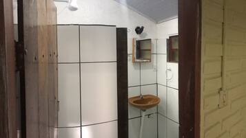 A small bathroom with white tiled walls, a wooden door, a single sink, and a mirror.