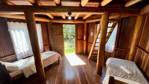 A rustic wooden cabin with two beds, a wooden ceiling, and a view of the outdoors. - Pousada Chapada dos Veadeiros (Alto Paraíso de Goiás)
