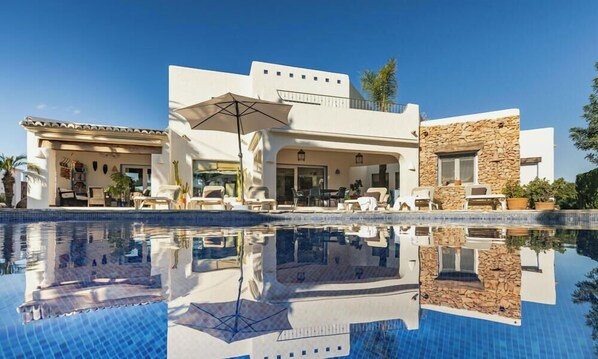A modern resort with a pool, outdoor seating, and a stone facade.