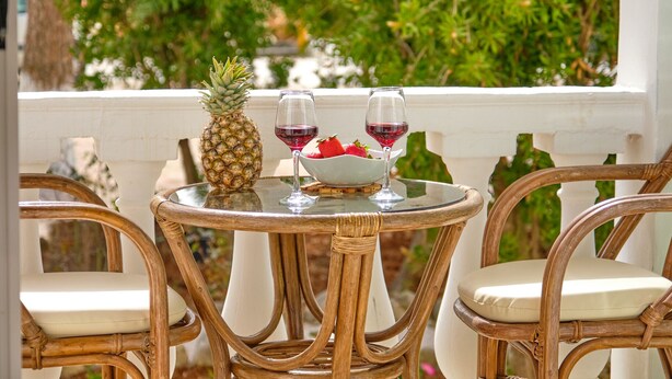 A round table with wicker chairs, a pineapple, two glasses of red wine, and a bowl of strawberries. - Katoi studio 3 Agios Georgios Pagoi (Corfu)