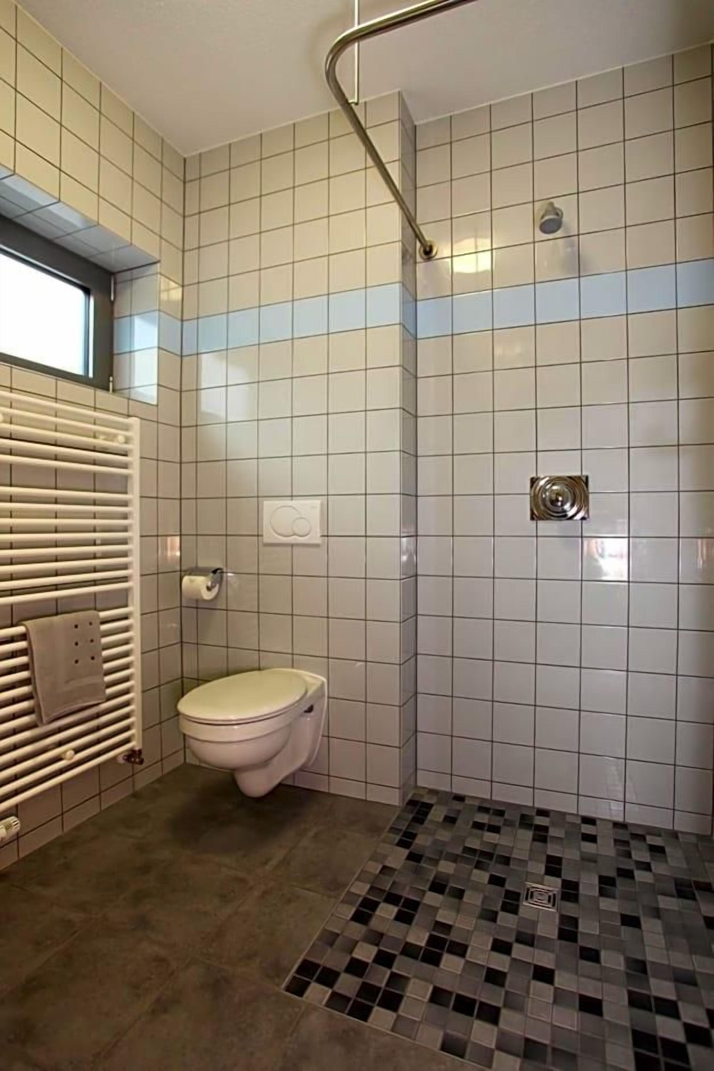Een badkamer met toilet, douche en betegelde vloer.