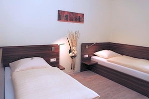 A room with two beds, a nightstand, a wall-mounted lamp, and a decorative vase. - Hotel Alter Zoll (Kleinblittersdorf)