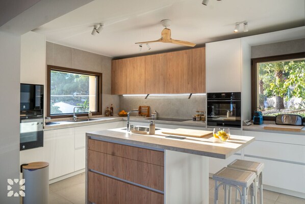 Une cuisine moderne avec des meubles en bois, un îlot central et une grande fenêtre offrant une vue sur la verdure.