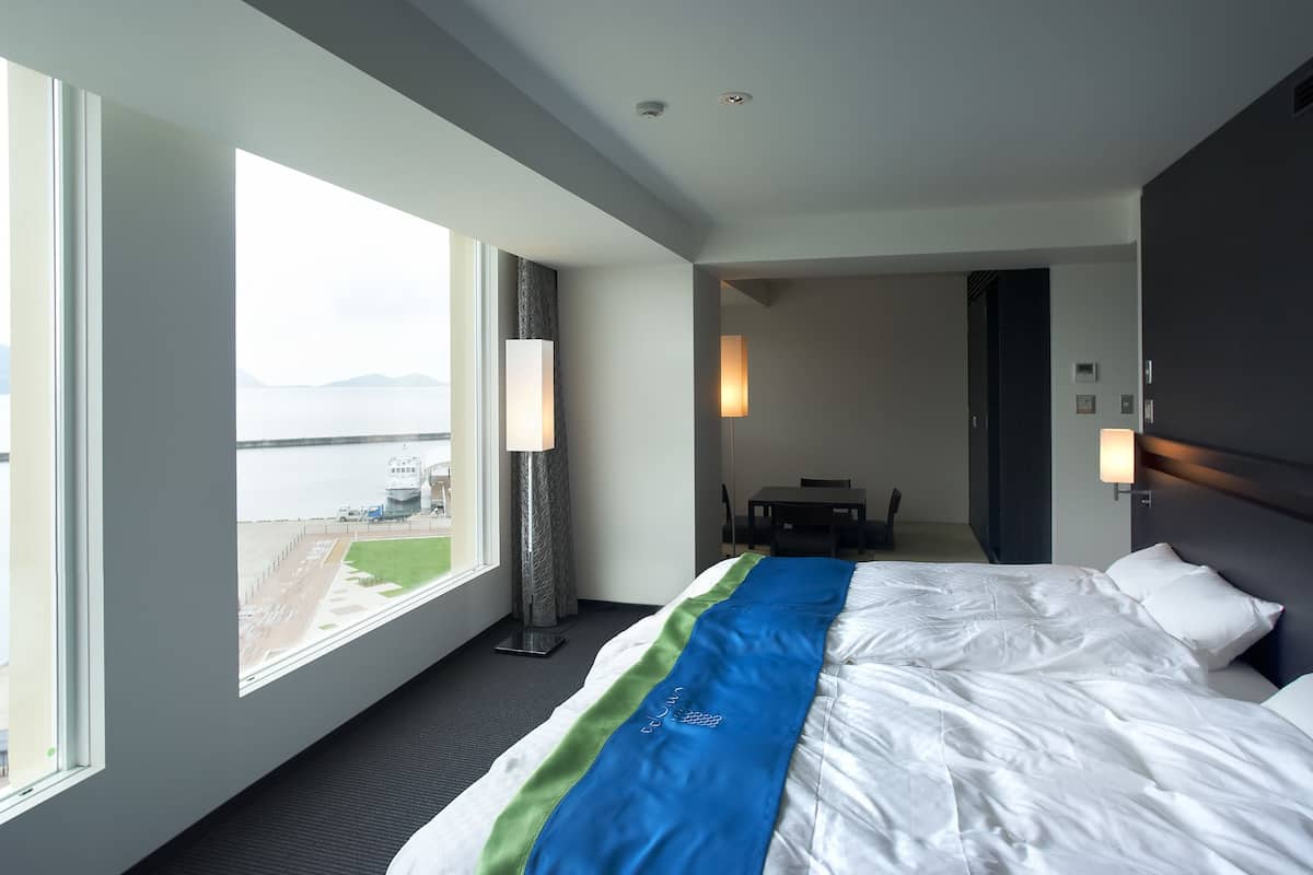 A hotel room with a large bed, a view of the airport, and a dining area.