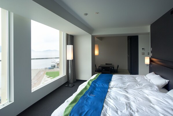 A hotel room with a large bed, a view of the airport, and a dining area. - Ocean Resort Hotel & Spa Uminpia (Ooi)