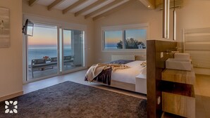A bedroom with a large bed, a view of the sea through sliding glass doors, and a modern bathroom with a wooden vanity. - Villa LIGHTHOUSE by Abahana Villas (Benitachell)