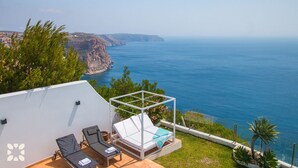 A terrace with a pool, sun loungers, and a view of the sea and cliffs. - Villa LIGHTHOUSE by Abahana Villas (Benitachell)