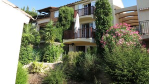 A multi-story residential building with balconies, surrounded by lush greenery and flowering plants. - Splendid sea view for this Var house 350m from the sea in a private domain. (Saint-Raphaël)