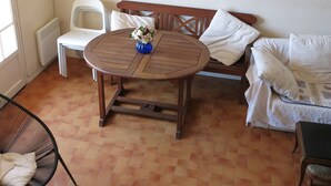 A cozy living room with a round wooden table, a white sofa, a bench, and a framed picture on the wall. - Splendid sea view for this Var house 350m from the sea in a private domain. (Saint-Raphaël)