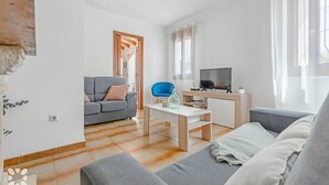 Ein modernes Wohnzimmer mit einem grauen Sofa, einem blauen Sessel, einem Holztisch und einem Fernseher auf einem Holzschrank.