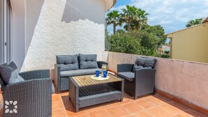 Eine Terrasse mit Korbmöbeln, einem Holztisch und einem blauen Getränk.
