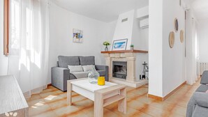 Ein Wohnzimmer mit grauem Sofa, weißem Couchtisch und Kamin.
