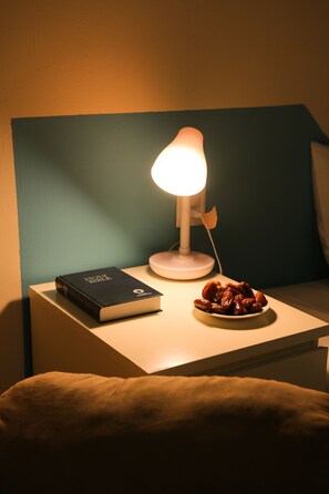 A bedside table with a book, a lamp, and a plate of dates.