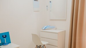 Une chambre d’hôtel équipée d’un lit, d’un bureau, d’une chaise, d’une commode et d’un panneau indiquant « Il est interdit de fumer ».