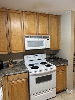 A kitchen with wooden cabinets, a white stove, and a microwave.