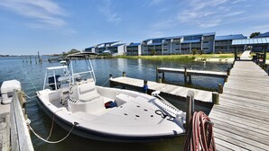 A boat docked at a pier with a building in the background. - Sundown B 13 (Pensacola)