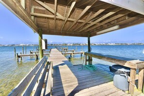 A wooden pier extending into calm water with a covered area at the end.