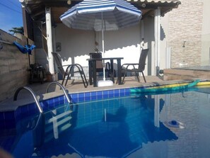 Una piscina al aire libre, sombrillas, sillones reclinables de piscina