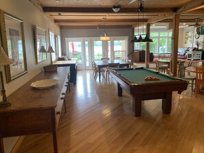 Ein geräumiges Zimmer mit Pooltisch, Holzboden und einem Essbereich mit Tisch und Stühlen.